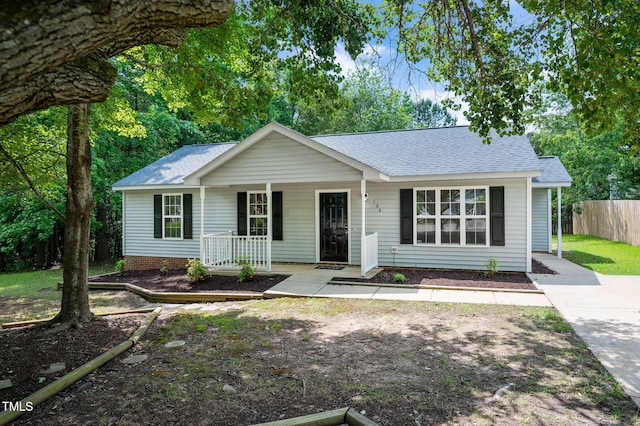 single story home with a shingled roof, a porch, and fence