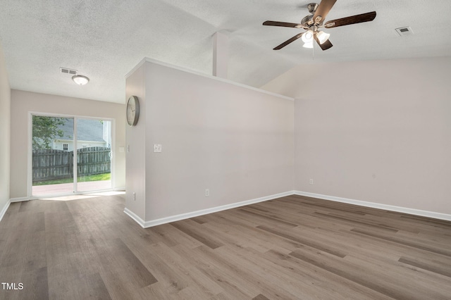 empty room featuring ceiling fan, wood finished floors, baseboards, a textured ceiling, and lofted ceiling