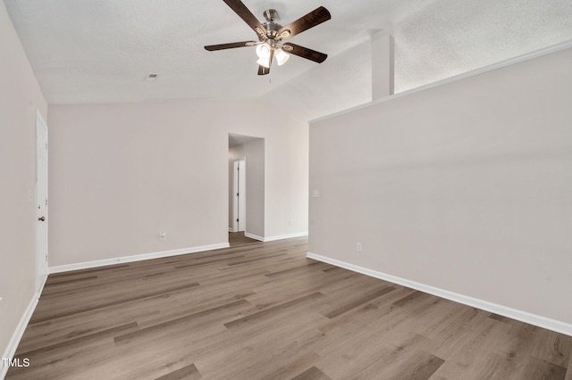 unfurnished room featuring ceiling fan, vaulted ceiling, wood finished floors, and baseboards