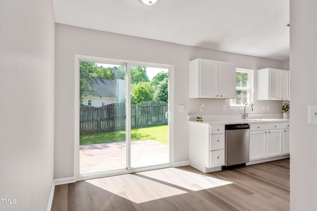 kitchen with dishwasher, light wood-style floors, light countertops, white cabinetry, and baseboards