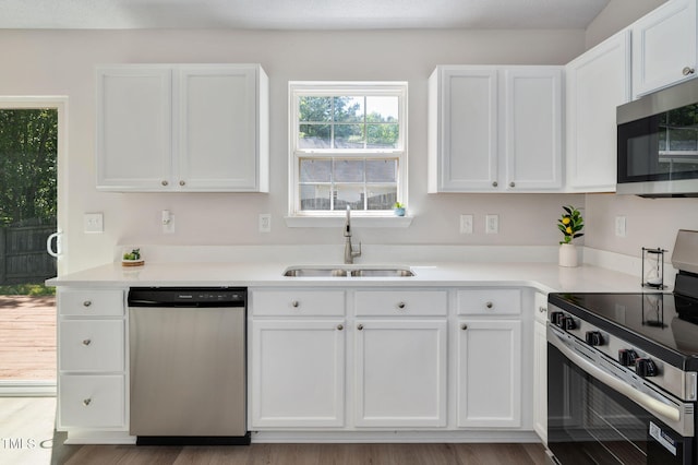 kitchen featuring appliances with stainless steel finishes, a sink, and white cabinets