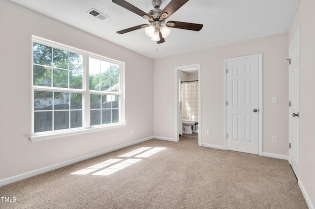 unfurnished bedroom with carpet flooring, baseboards, ensuite bath, and ceiling fan
