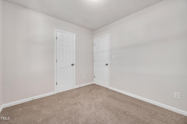 carpeted spare room with baseboards and a textured ceiling