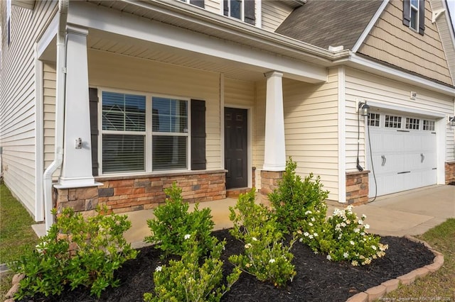1409 Amen Ct, Hope Mills, NC 28348 - view of exterior entry with covered porch, stone siding, a garage, driveway, and a shingled roof