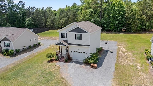 view of front of property featuring gravel driveway, an attached garage, a front lawn, and a wooded view