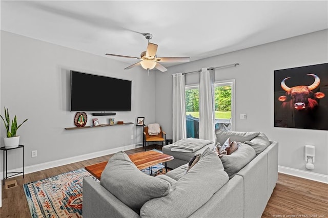 living room featuring ceiling fan, wood finished floors, and baseboards