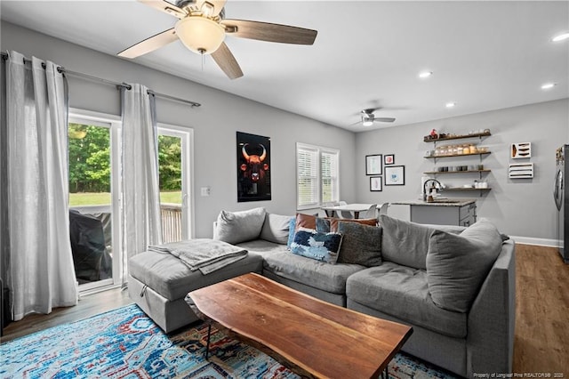 living room with ceiling fan, wood finished floors, recessed lighting, bar area, and baseboards