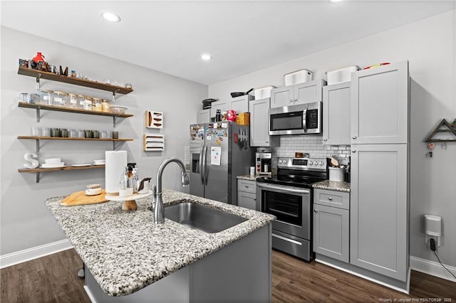 kitchen featuring appliances with stainless steel finishes, a sink, dark wood-style floors, baseboards, and tasteful backsplash