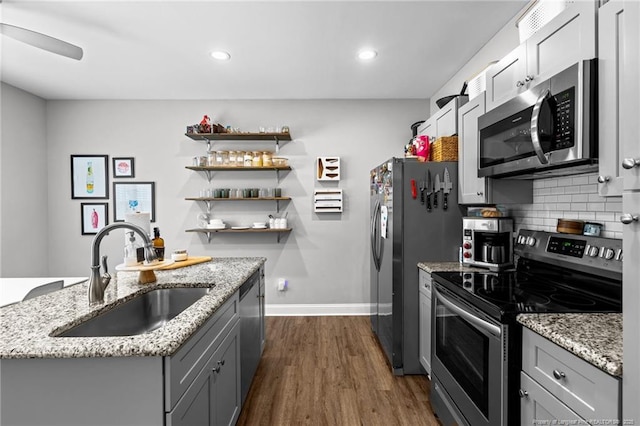 kitchen with appliances with stainless steel finishes, a sink, baseboards, gray cabinetry, and tasteful backsplash