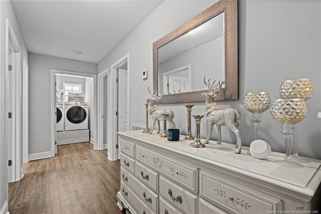 hall with separate washer and dryer, wood finished floors, and baseboards