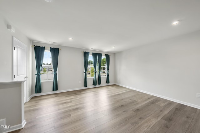 spare room with wood finished floors, baseboards, and recessed lighting