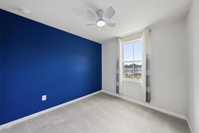 carpeted empty room with a smoke detector, ceiling fan, and baseboards