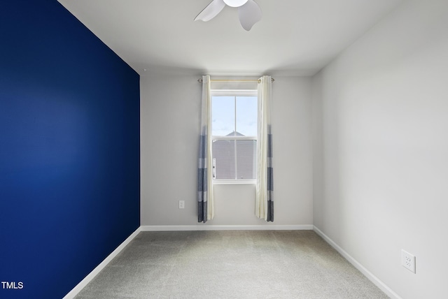 carpeted empty room with a ceiling fan and baseboards