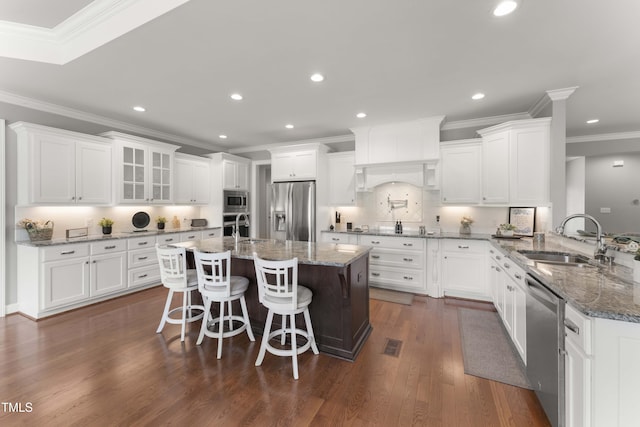 kitchen featuring stainless steel appliances, a sink, ornamental molding, white cabinetry, and recessed lighting