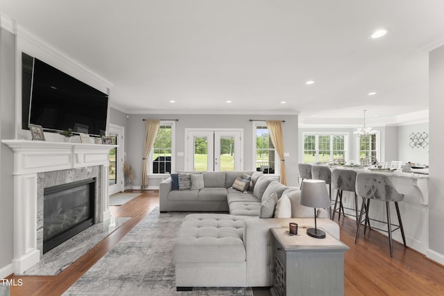 living room with plenty of natural light, ornamental molding, wood finished floors, recessed lighting, and a fireplace