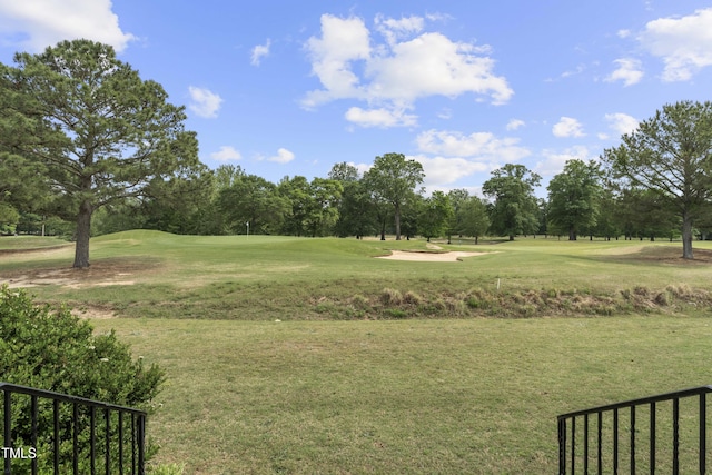view of home's community featuring view of scattered trees, golf course view, and a lawn