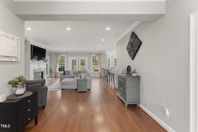 living room with a fireplace, recessed lighting, wood finished floors, crown molding, and baseboards