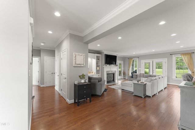 living room with ornamental molding, dark wood-style floors, a glass covered fireplace, recessed lighting, and baseboards
