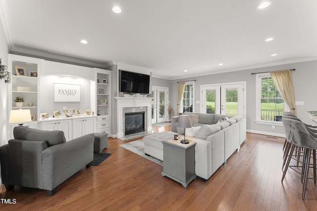 living room featuring ornamental molding, dark wood-style floors, a glass covered fireplace, french doors, and recessed lighting