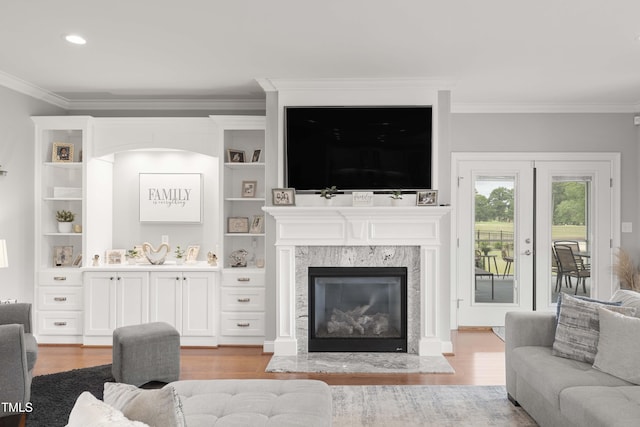 living area featuring ornamental molding, wood finished floors, a high end fireplace, french doors, and recessed lighting