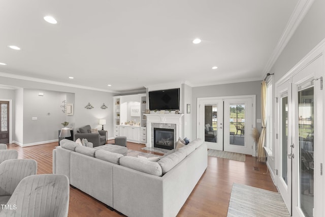 living room with french doors, ornamental molding, recessed lighting, wood finished floors, and a high end fireplace