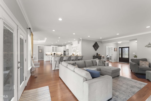 living area with wood finished floors, french doors, recessed lighting, ornamental molding, and baseboards