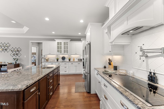 kitchen featuring black electric stovetop, a sink, freestanding refrigerator, white cabinets, and dark brown cabinets