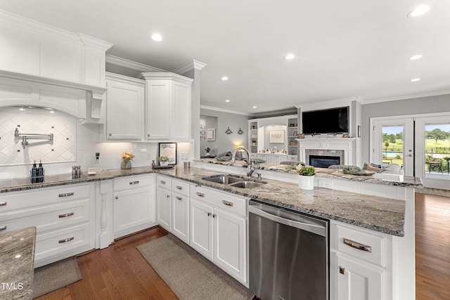 kitchen with stainless steel dishwasher, a sink, a peninsula, dark wood-style flooring, and open floor plan