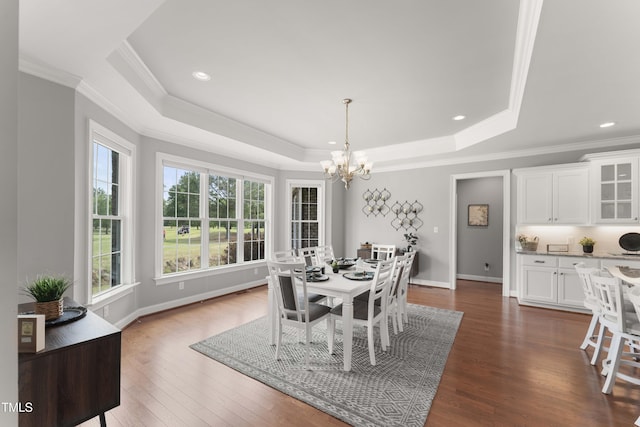 dining room with a chandelier, a tray ceiling, ornamental molding, dark wood-style floors, and baseboards