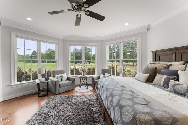 bedroom featuring multiple windows, crown molding, baseboards, wood finished floors, and ceiling fan