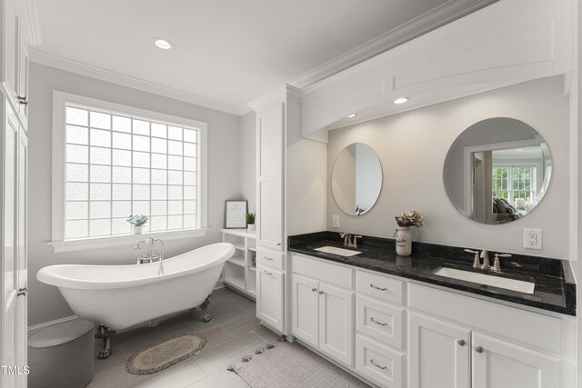 bathroom featuring crown molding, a soaking tub, double vanity, and recessed lighting