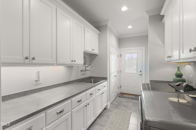 kitchen with independent washer and dryer, a sink, ornamental molding, white cabinets, and recessed lighting