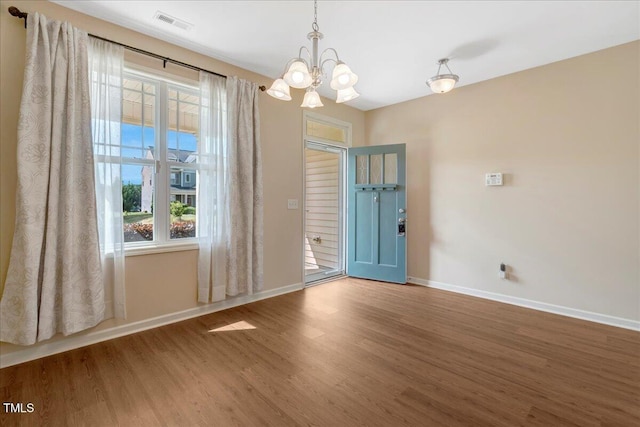 unfurnished dining area featuring baseboards, wood finished floors, a chandelier, and plenty of natural light