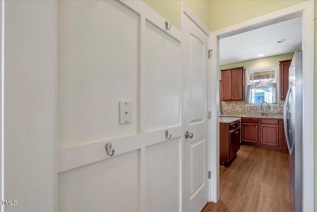 corridor featuring light wood-style flooring and a sink