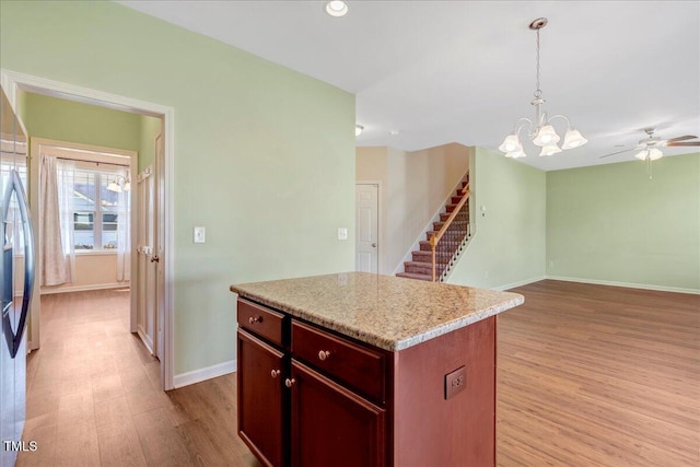 kitchen featuring light wood finished floors, pendant lighting, baseboards, a kitchen island, and light countertops