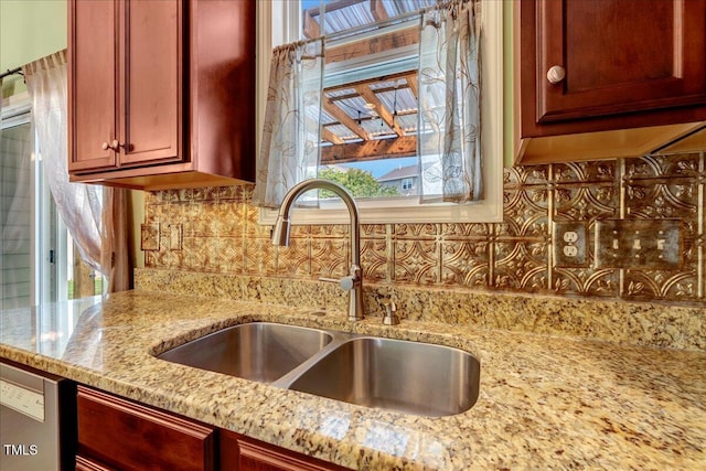 kitchen view of a sink, decorative backsplash, light stone counters, dark brown cabinets, and dishwasher