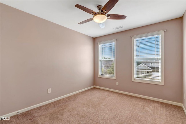 empty room with light colored carpet, baseboards, and a ceiling fan