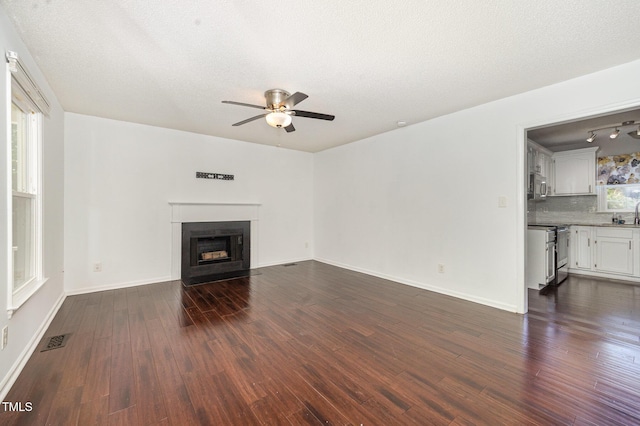 40 Crepe Myrtle Ct, Angier, NC 27501 - unfurnished living room featuring a ceiling fan, dark wood finished floors, a fireplace with flush hearth, baseboards, and a textured ceiling
