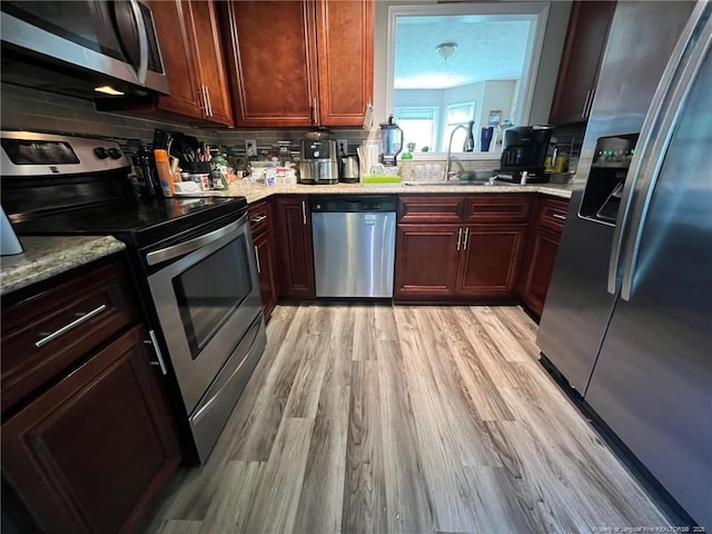 6651 Brookshire St, Fayetteville, NC 28314 - kitchen with stainless steel appliances, a sink, light wood-style floors, decorative backsplash, and light stone countertops