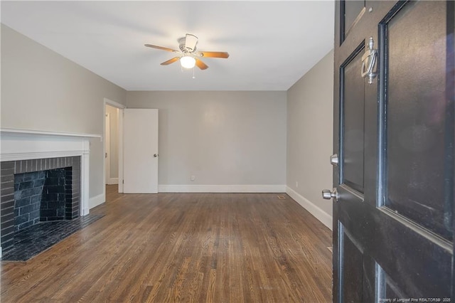 unfurnished living room with a ceiling fan, wood finished floors, baseboards, and a brick fireplace