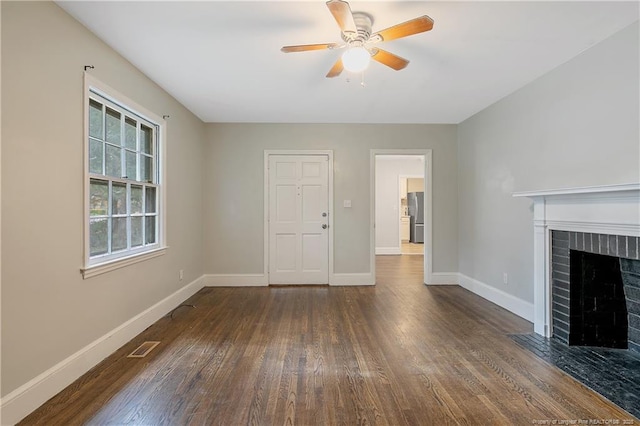 unfurnished living room with dark wood finished floors, a ceiling fan, baseboards, and a brick fireplace