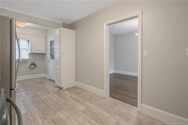 clothes washing area with light wood finished floors and baseboards