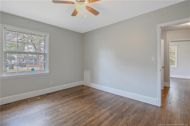 unfurnished room with dark wood finished floors, a ceiling fan, and baseboards