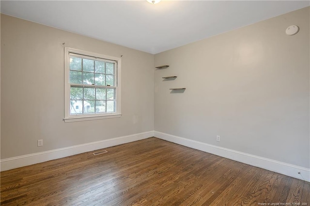 spare room featuring baseboards, wood finished floors, and a smoke detector