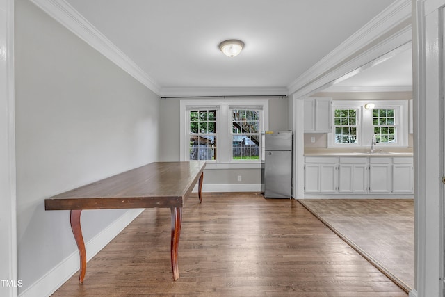 302 Hester St, Knightdale, NC 27545 - unfurnished dining area featuring wood finished floors, crown molding, baseboards, and a sink