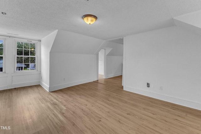 302 Hester St, Knightdale, NC 27545 - additional living space with wood finished floors, a textured ceiling, vaulted ceiling, and baseboards