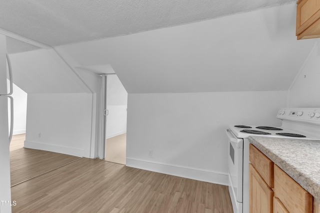 302 Hester St, Knightdale, NC 27545 - kitchen with electric stove, light wood-style floors, light countertops, light brown cabinetry, and lofted ceiling