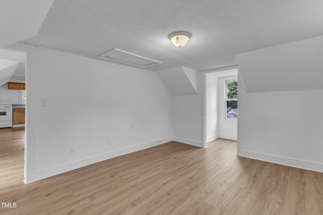 302 Hester St, Knightdale, NC 27545 - additional living space with light wood-style flooring, a textured ceiling, attic access, lofted ceiling, and baseboards