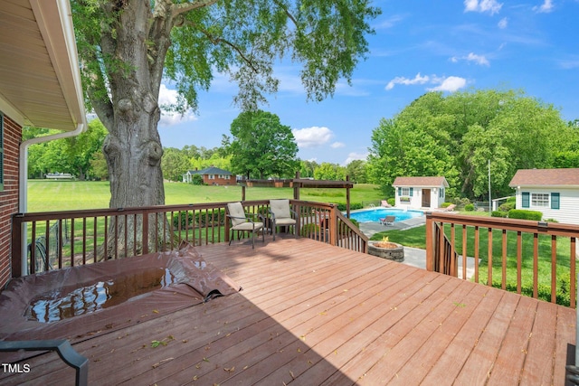 deck with an outdoor structure, a yard, an outdoor fire pit, and view of wooded area