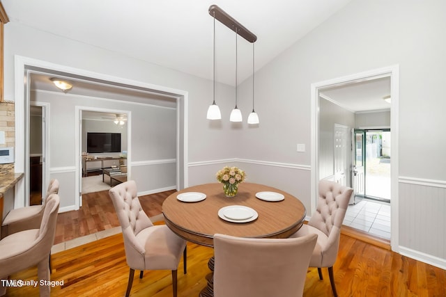 dining room with light wood-style flooring and vaulted ceiling